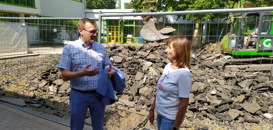 Bürgermeister Christian Seitz im Gespräch mit Stefani Petermann vom Kitateam vor Baggern auf em Schulhof.