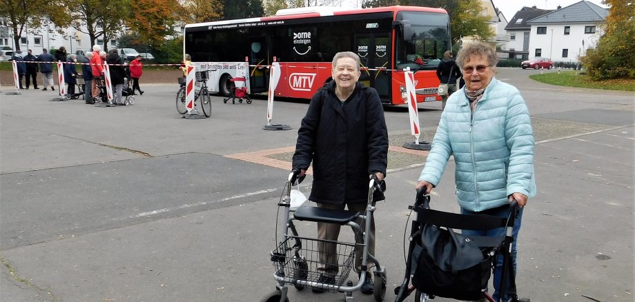 Zwei ältere Damen mit Rollator vor einem Linienbus.