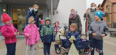 Bürgermeister und Erzieherinnen mit Kindern und vollen Müllsäcken vor der Kita Vogelnest.