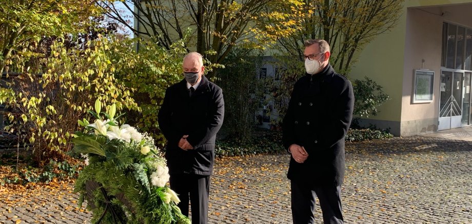 Bürgermeister Seitz und Bodo Knopf, Vorsitzender der Gemeindevertretung, vor einem Kranz auf dem Friedhof.