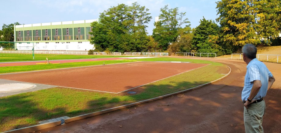 Man sieht im Vordergrund die neue Weitsprung- und Kugelstoßanlage, im Hintergrund das grüne Fußballfeld.