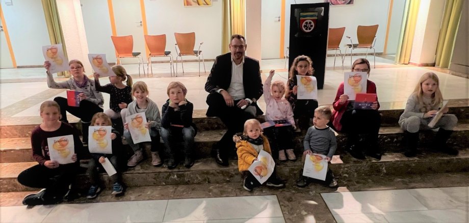 KLeine Kinder mit Urkunden sitzen um Bürgermeister Seitz herum auf einer Treppe.