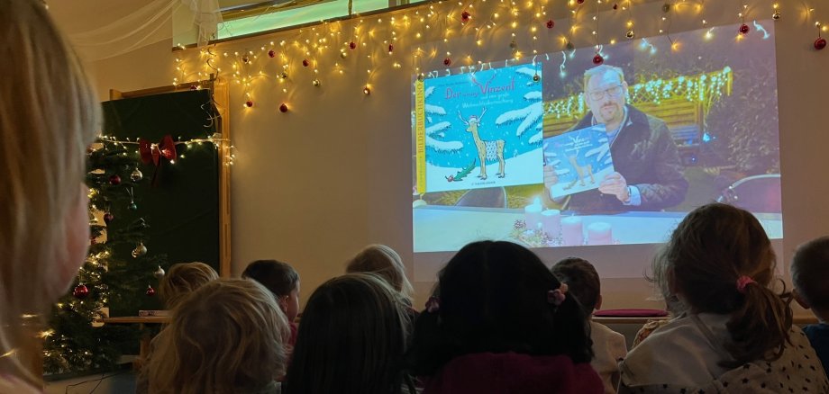 Der Bürgermeister auf der Leinwand, Kinder sitzen davor und staunen.