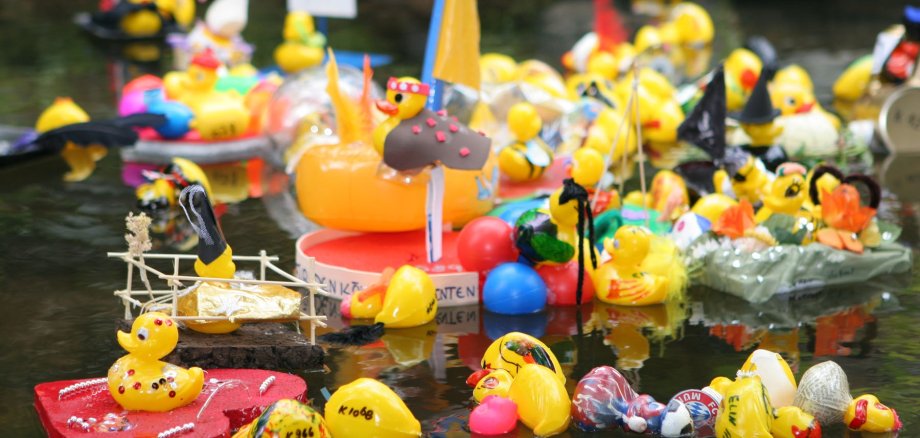 Viele kleine geschmückte Enten im Wasser.