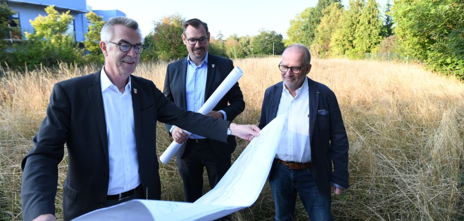 Franz Jirasek, Christian Seitz und Harald Treber schauen sich auf dem Grundstück an der Raiffeisenstraße Pläne an.