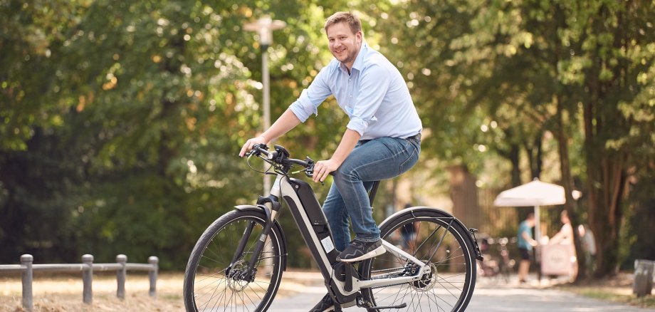 Ein fröhlich dreinschauernder Mann testet ein E-Bike.