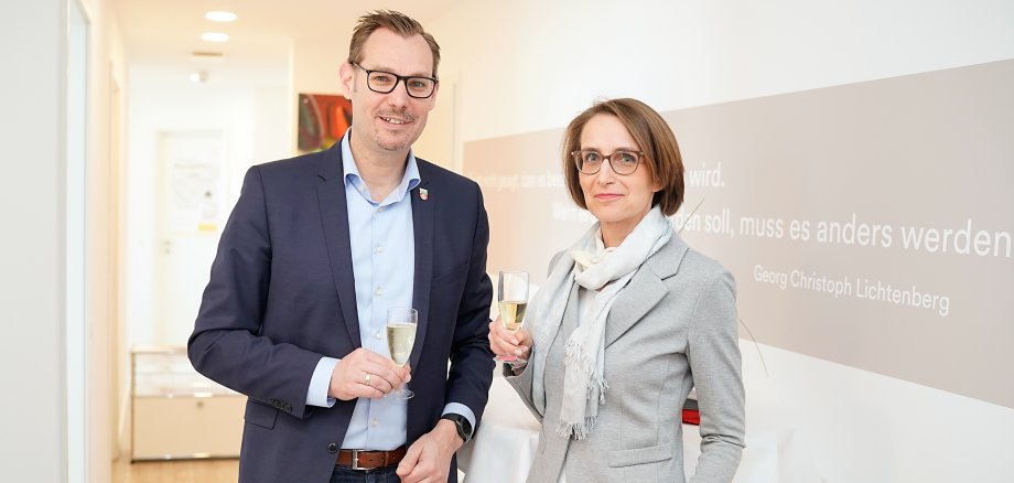 Bürgermeister Seitz und Anja Pietzsch mit einem Glas Sekt in den Praxisräumen.