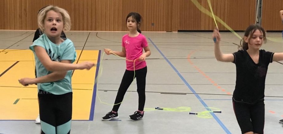 Seilspringende Kinder in der Turnhalle.