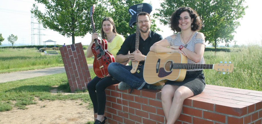 Drei MItglieder der Band MissTune(d) sitzen auf einem Ziegelblock im Ziegeleipark.