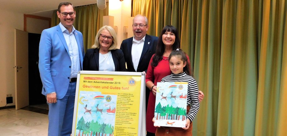 Großer Bahnhof im Rathaus: Die kleine Künstlerin hält inmitten von Offiziellen den von ihr gestalteten Adventskalender in die Höhe.