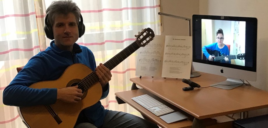 Thorsten Müller mit Gitarre und Kopfhörern vor seinem PC.