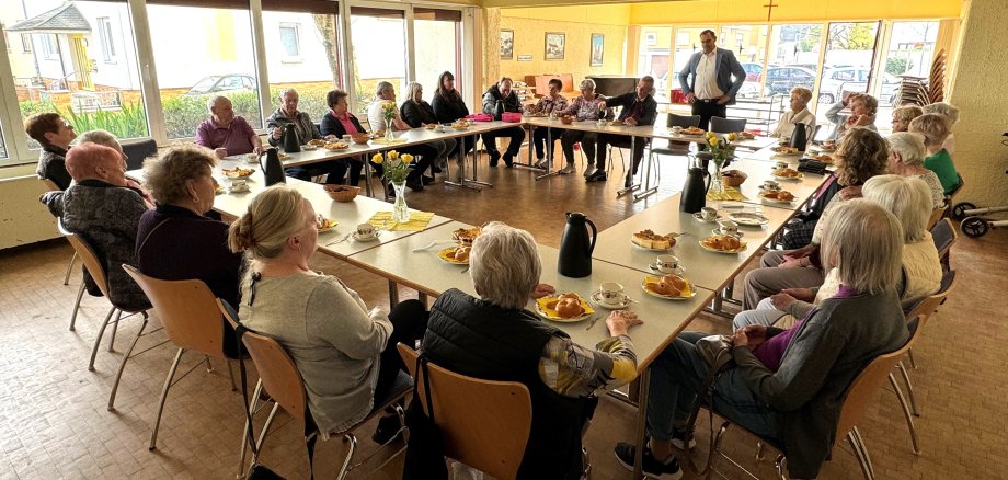 Die Bewohner an großer Kaffeetafel.